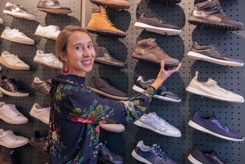 Anya smiling at the camera standing in front of a wall of displayed Groundies barefoot shoes