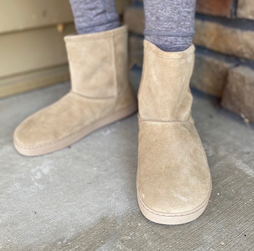 A close up of a pair of feet wearing beige Groundies Barefootwear Cozy barefoot boots for fall winter