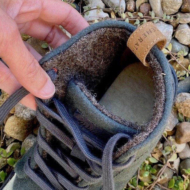 A hand holding open Wildling Shoes Chokeberry wool autumn barefoot boots showing the wooly insole