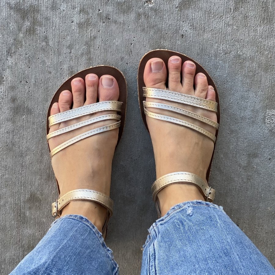 Top Down view of a woman with wide toe splay wearing handmade gold leather sandals from Jenon Leather, a barefoot shoe brand in the Czech Republic