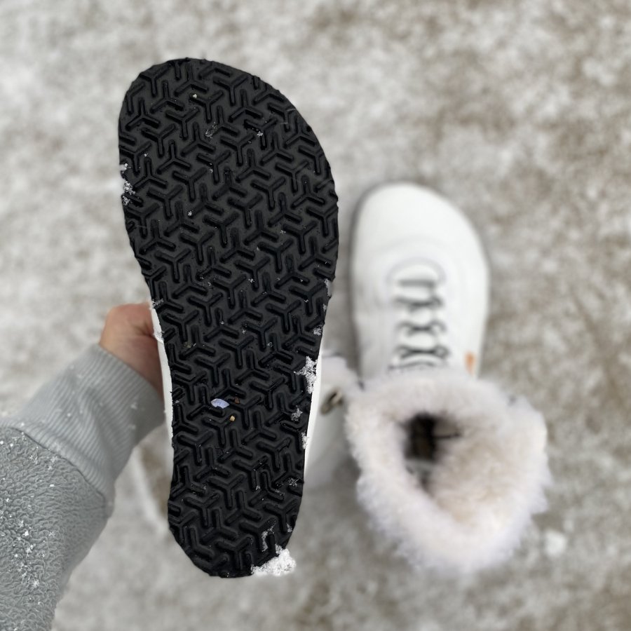 Close up of Snowflake boots outsole from Jenon Leather, the close up boot is behind held by a hand, and the other boot can be seen in the background on snowy ground