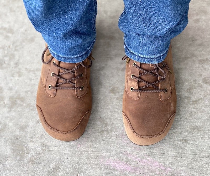 a top down view of a man wearing jeans and brown Denver Leather barefoot boots from Xero shoes