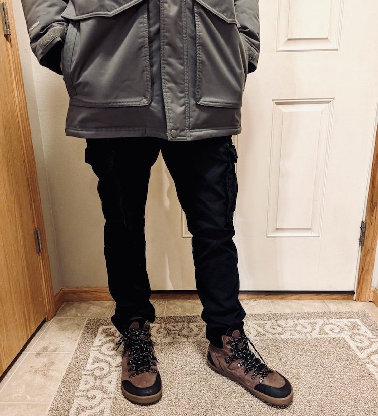 A man standing in his entry way wearing a coat and brown Be Lenka Ranger barefoot boots