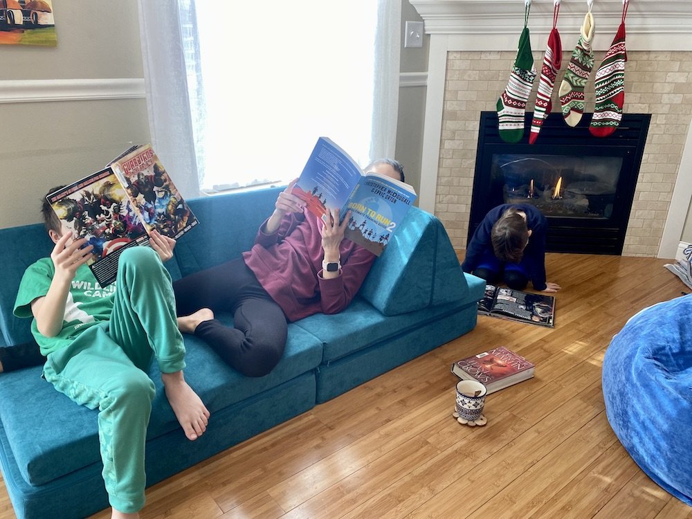 a living room with a bean bag and low couch for furniture all sitting around reading