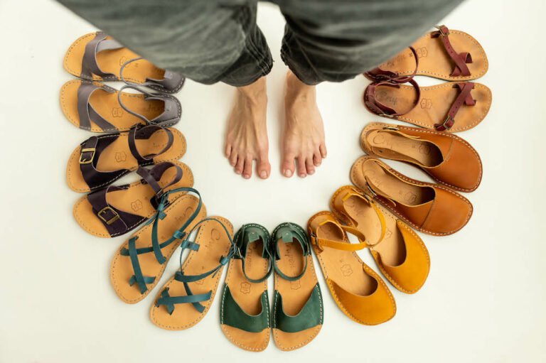 A arch of Crupon Sandals barefoot shoes in rainbow colors surrounding a pair of bare feet