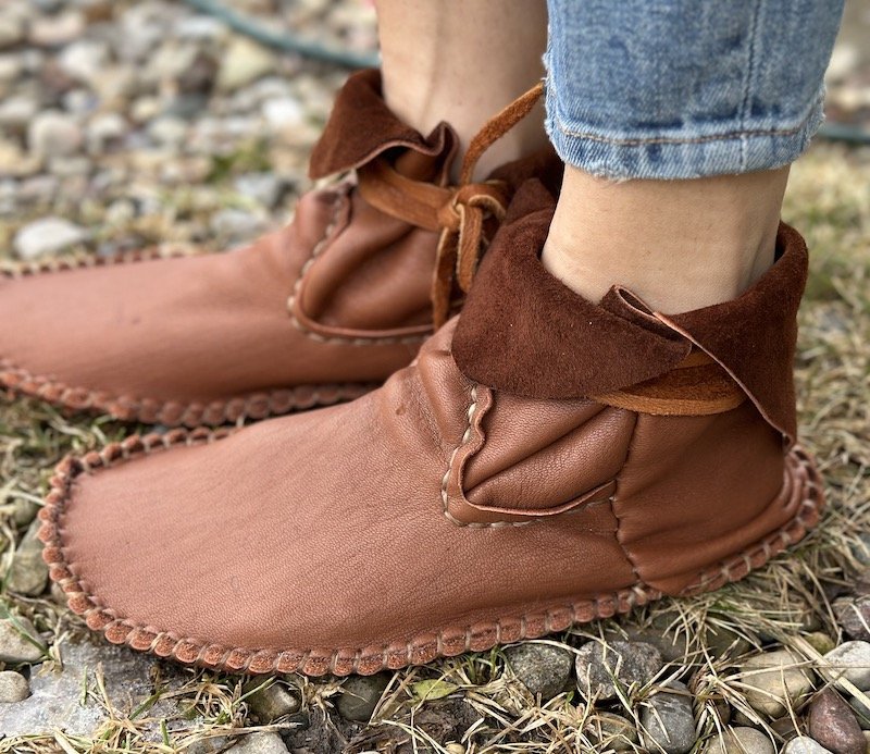 A side view of a pair of feet wearing FaeMoon Wolf custom moccasins leather barefoot shoes for grounding