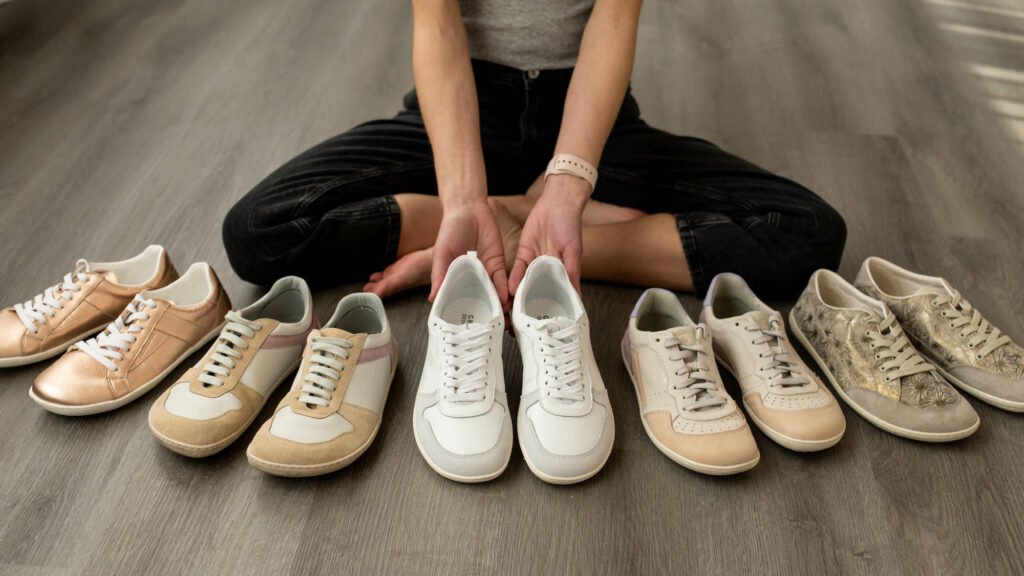 A row of stylish barefoot sneakers from Groundies with a person behind holding one pair