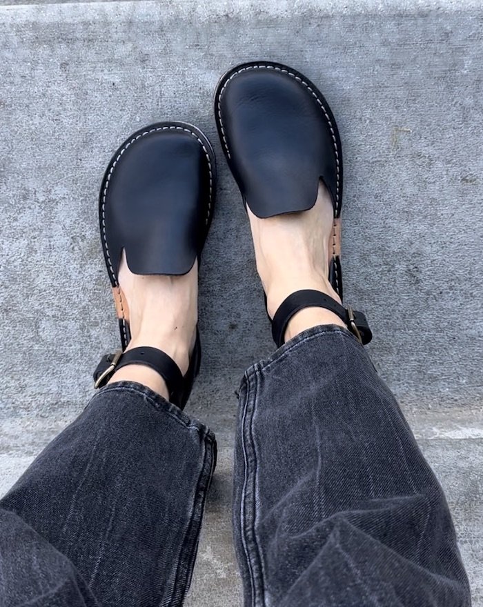 A top down view of a pair of feet wearing black Crupon Sandals Iris - barefoot flats