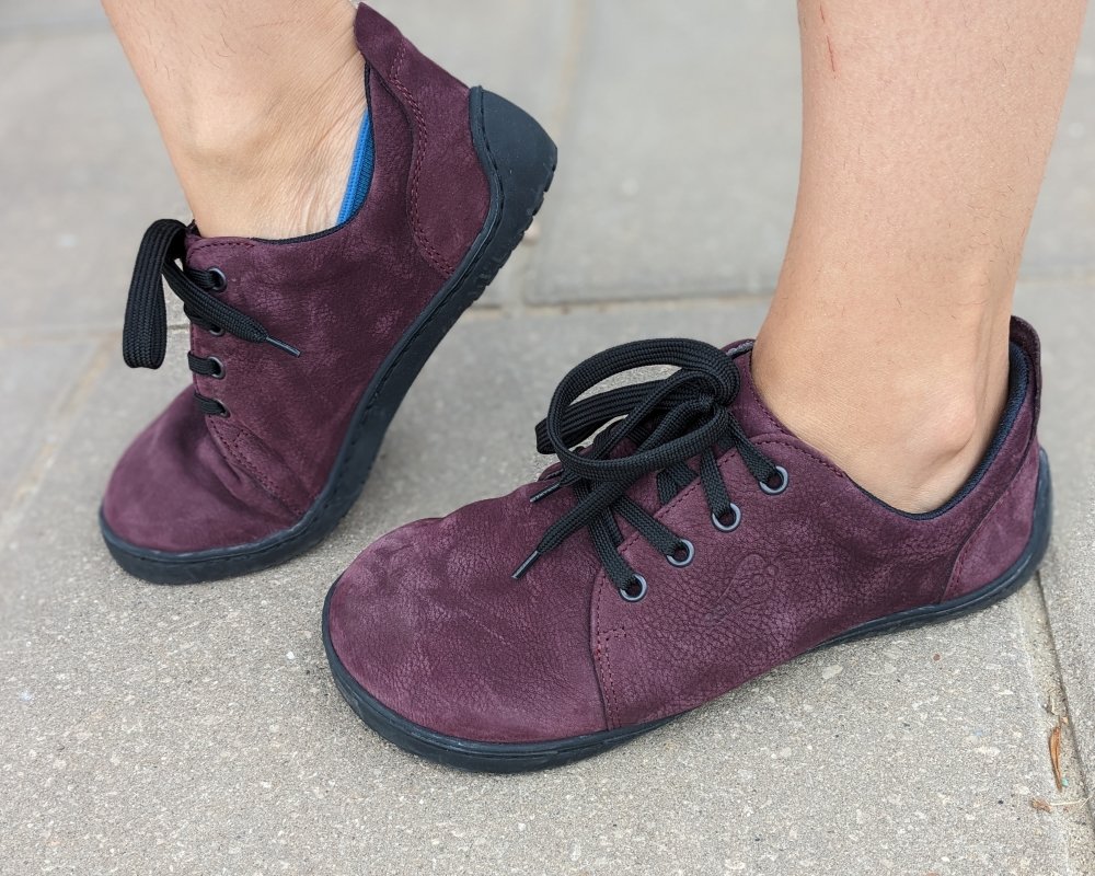 A single angle close up of a pair of purple City Jungle barefoot sneaker from Realfoot. The shoe in the back is flexed up