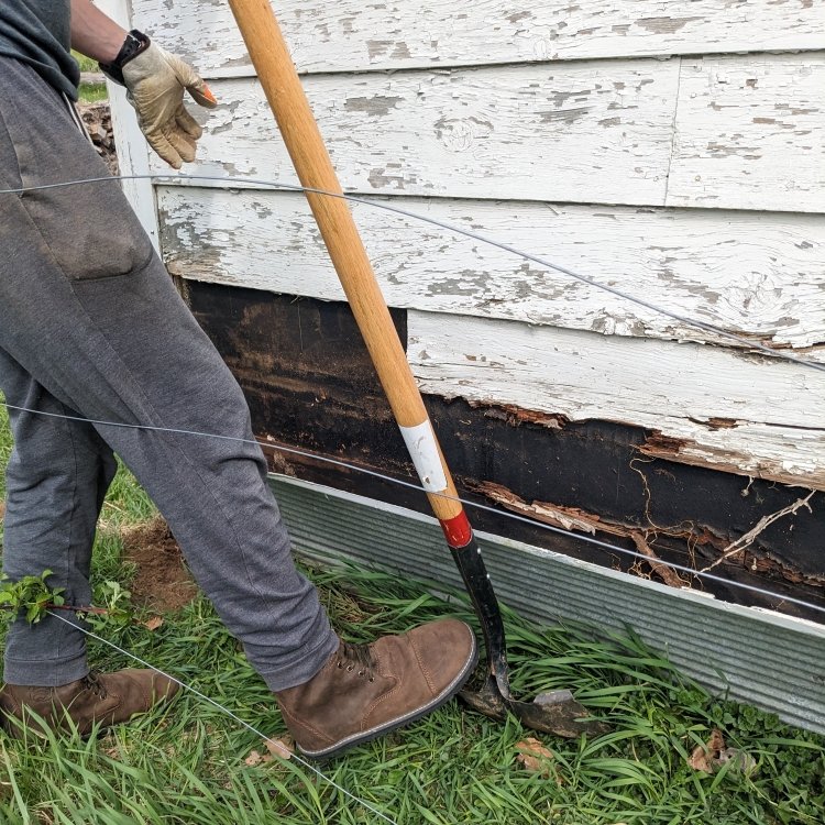 A man wearing Bearfoot Bruins with a shovel on the outside of a building. The hefty zero drop sole is beneficial for shoveling