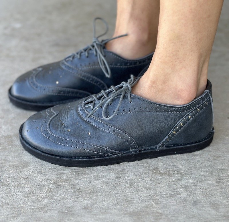 A side view of a pair of feet wearing Softstar Shoes oxfords barefoot dress shoes in Orion grey, regular width