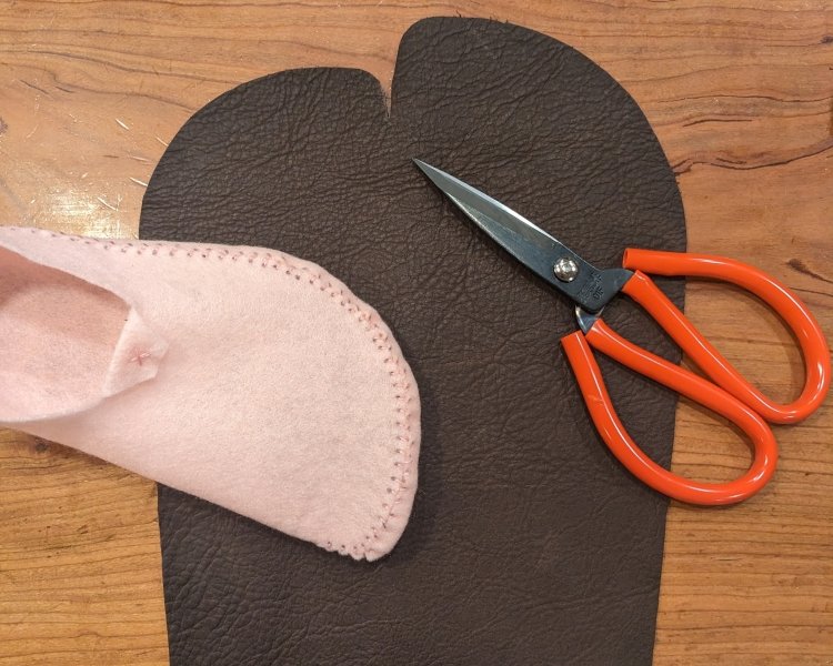 A pair of leather scissors, test felt moccasin, and 1 leather moccasins pattern cut out