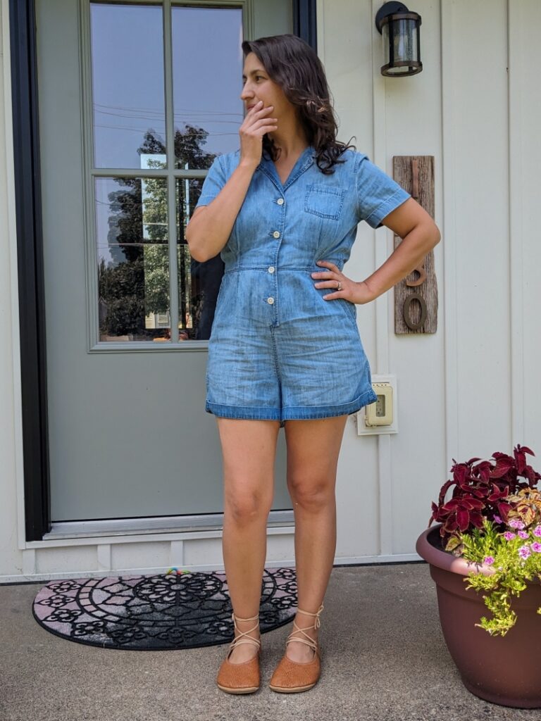 Full body image of a woman with dark brown hair in a chambray Romper standing on her front steps wearing cognac faux woven flats from Everleigh meadow in hideaway laceup style Regular width anatomical shoes for women