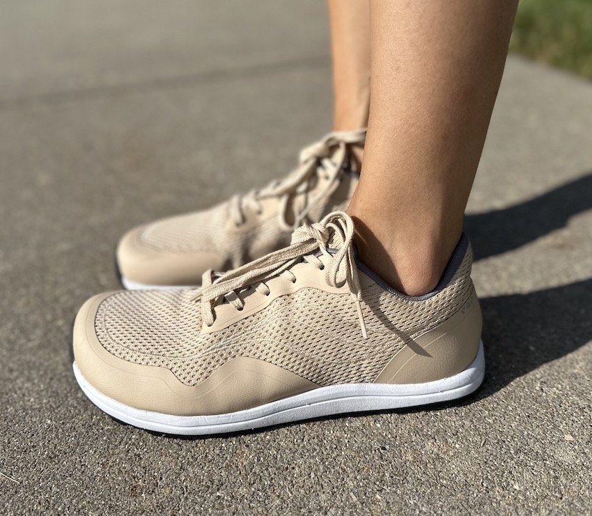 A side view of a person standing on pavement wearing Bahe barefoot running shoes in Sand color with grounding technology