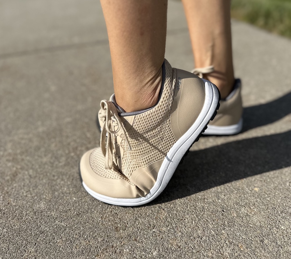 A side view of a person wearing Bahe barefoot running shoes with grounding technology and the foot flexed to show the sole is flexible