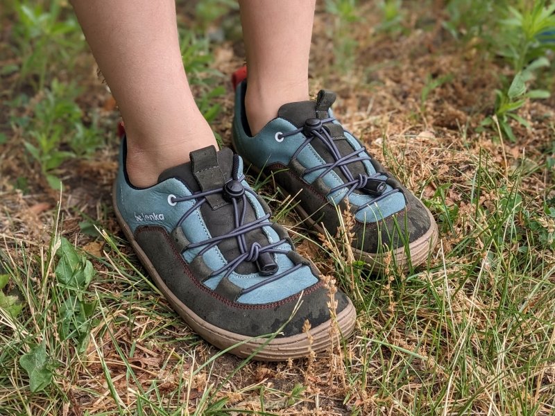 A close up of a child wearing the Be Lenka Xplorer kids barefoot shoes on grass which are great for back to school