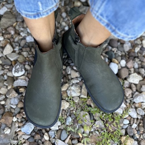 Top view of deep gray green Chelsea boots from Koel barefoot wide toe box chelea boots with a zipper being worn on rocks