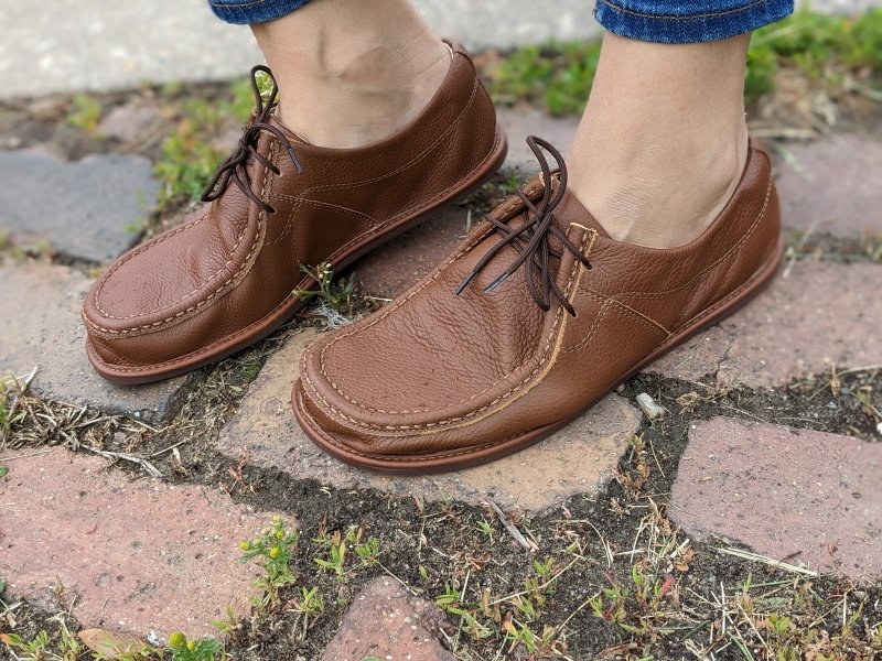 Side angled view of a pair of women's feet on a brick path wearing Magical Shoes Cameron soft flexible barefoot lace ups