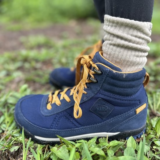 Xero Shoes Close up of navy Ridgeway comfortable hiking boots being worn with scrunched up socks. The side view shows the zero drop outsole