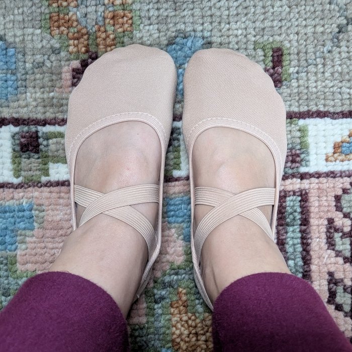 A woman with extra wide feet wearing a pair of men's Bloch Performa Canvas Stretch ballet shoes in tan.