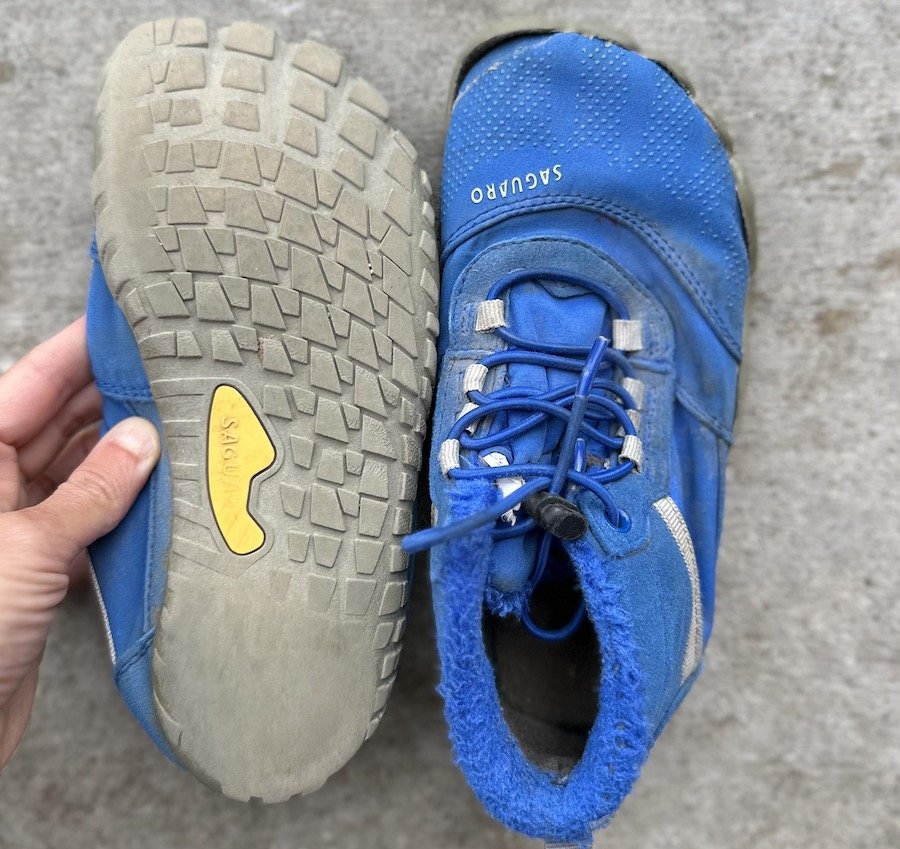 a close up of a pair of well worn kids barefoot winter shoes from Saguaro called the Will in blue color