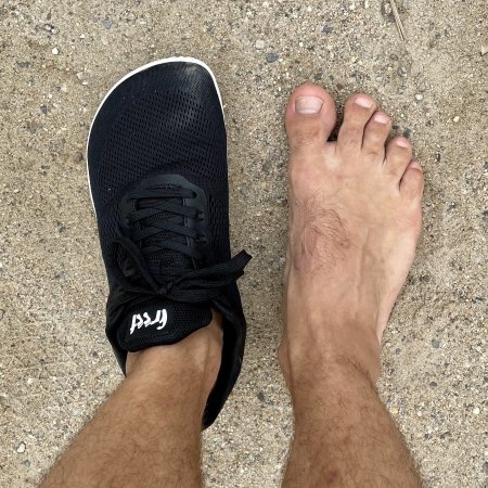 Top down view of a bare foot next to a foot wearing Freet Vibe mesh sneakers for in and out of the gym with a wide anatomical toe box