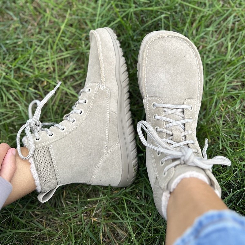 a close up of a pair of feet on grass wearing Lems Barefoot boots the Telluride showing the wide toe box and zero drop sole.