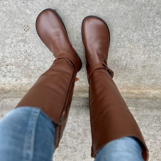 Top down view of Brown tall leather Shapen Glam boots with wide toe box being worn with light jeans