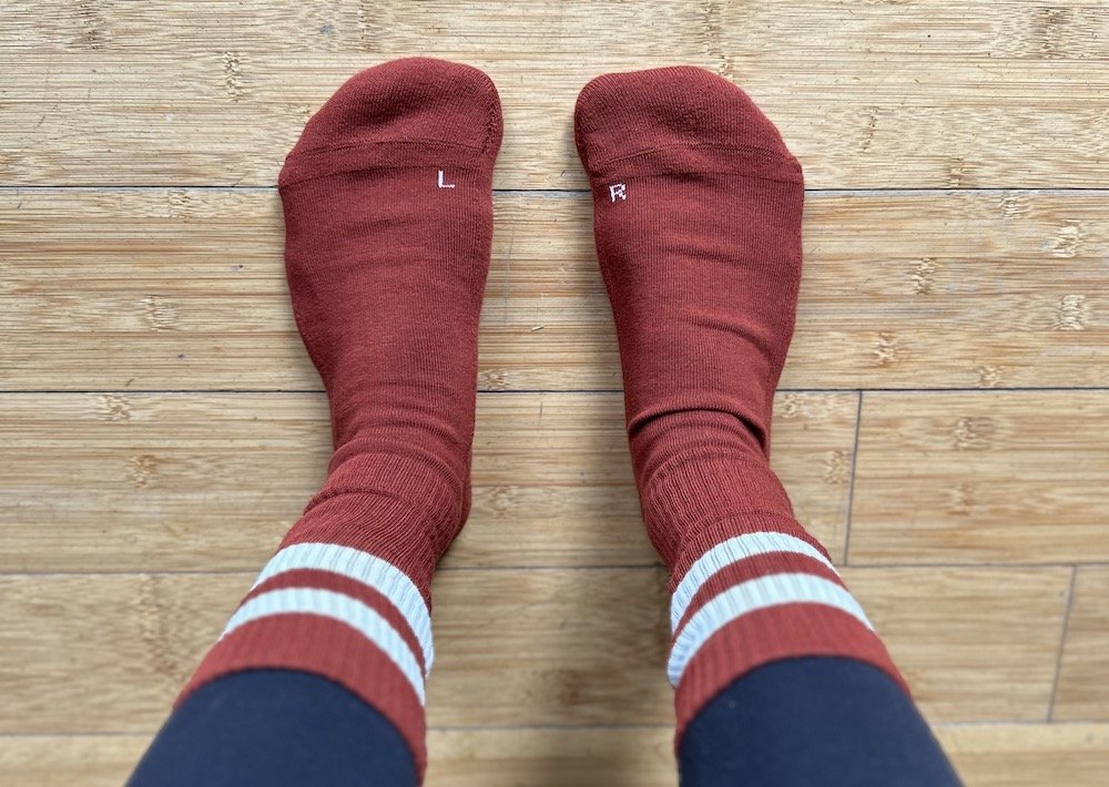 a top down view of a pair of feet wearing anatomical socks from Mukishoes with a wide toe box and a left and right sock - they are barefoot friendly