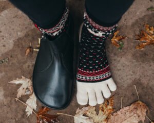 a top down view of a foot standing on concrete wearing cozy warm toe socks with barefoot shoes