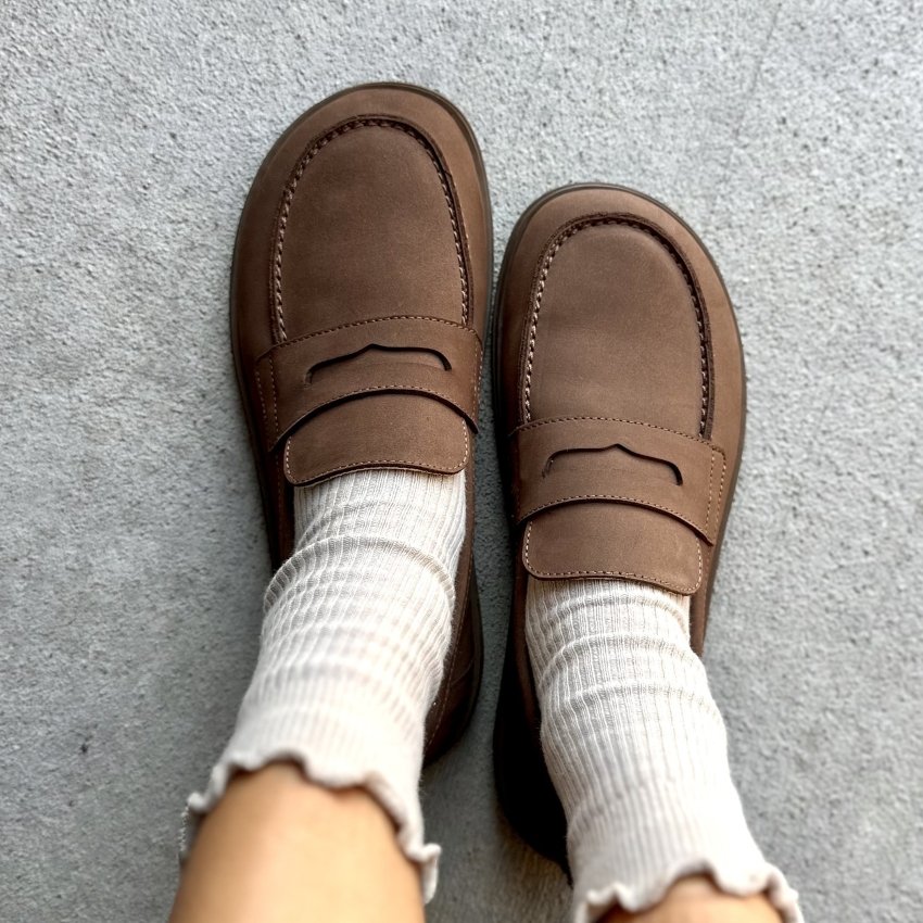 A top down view of a pair of Groundies Brisbane barefoot loafers in a warm brown leather with a wide toe box and paired with a cute ruffle socks.