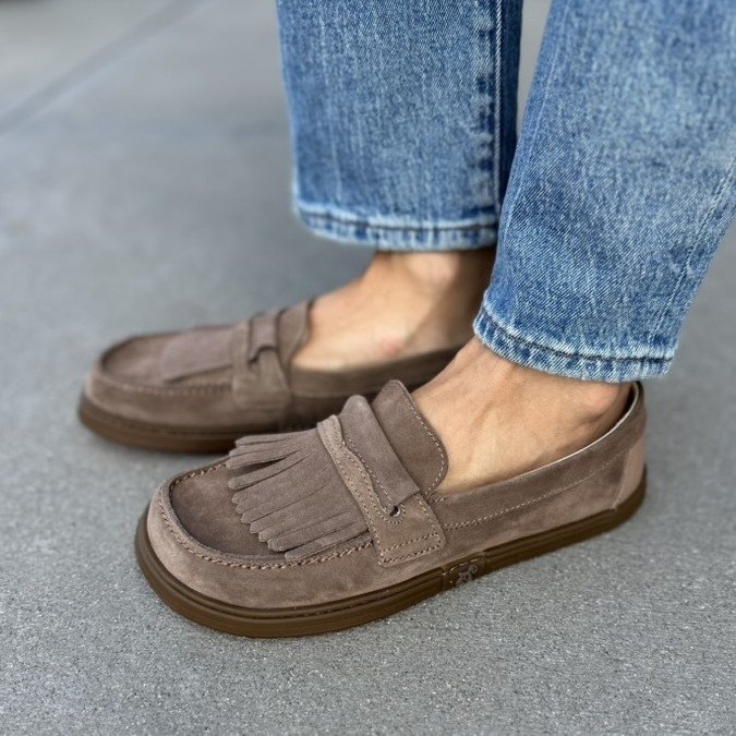 A woman's feet standing at an angle in a pair of Magical Shoes Pienza loafers with optional fringe detail and a wide toe box