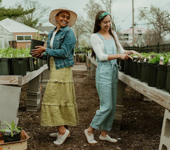 Two women' standing outside gardening wearing Mukishoes hemp canvas barefoot sneakers