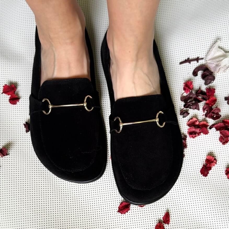 Top down view of a person's feet in zeazoo cheetah black loafers with metal detail