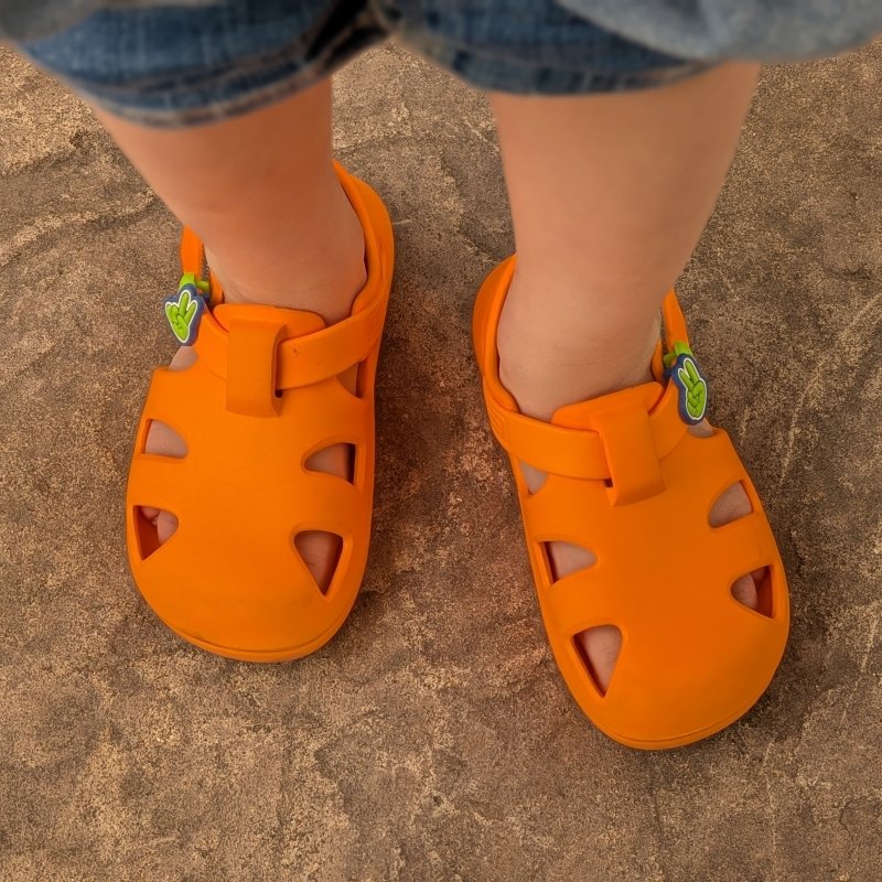 Ten Little splash sandal from the top down in neon orange being worn by a toddler.