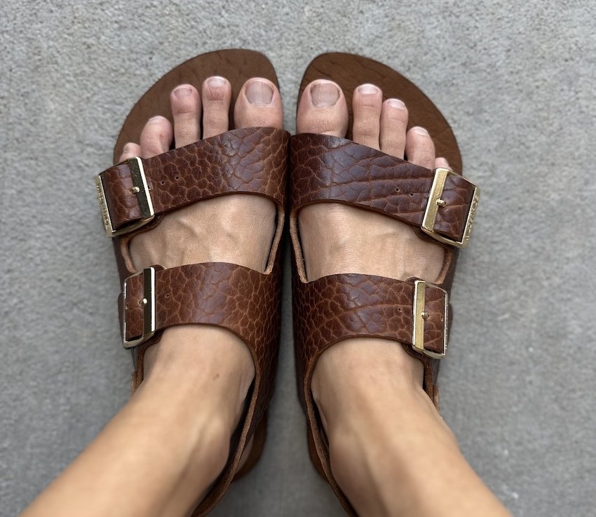 A pair of feet close up wearing Wildstride barefoot sandals handmade in the USA from Bison leather