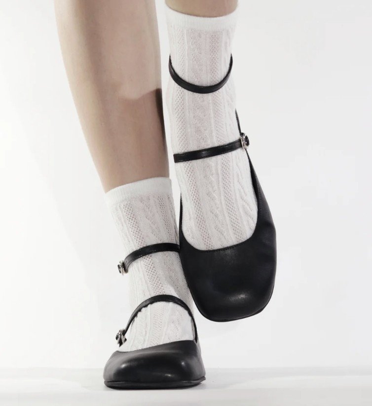A pair of vegan barefoot mary janes from High Feels with an ankle strap, worn with white lace socks