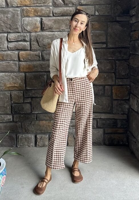 A woman posing for the camera wearing brown gingham pants and Jenon Leather Villet two strap for Anya's Shop wide toe box barefoot mary janes.