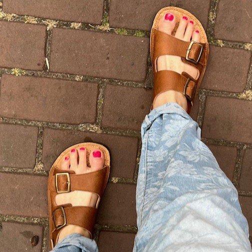 Koel Ada double buckle leather strap sandal being worn on a brick patch