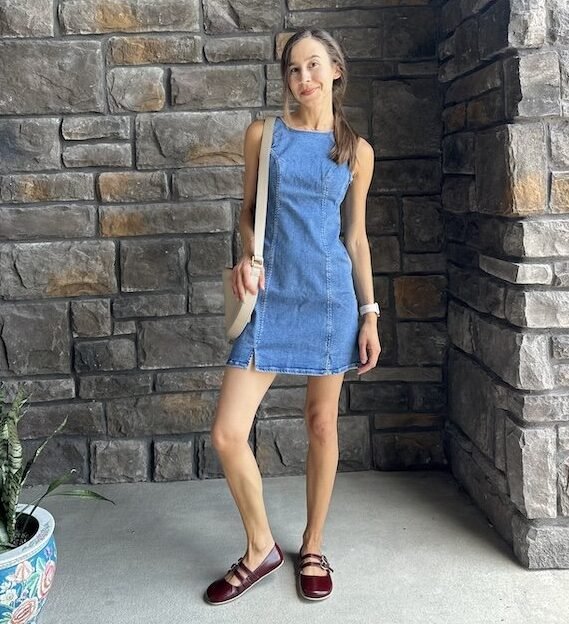 A woman posing for the camera wearing a denim dress and Origo Shoes barefoot mary janes in burgundy leather with two straps