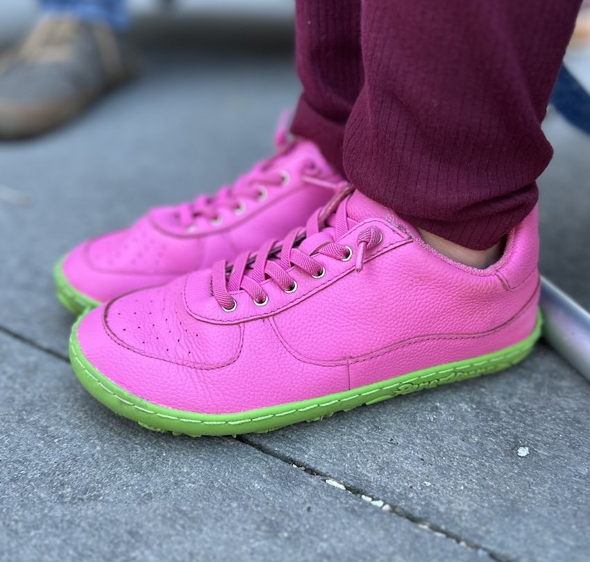 A close up side view of a child's feet wearing PaperKrane hot pink kids barefoot sneakers