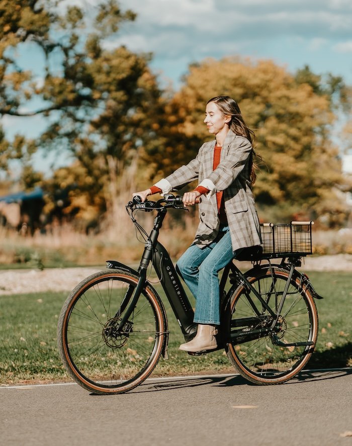 Anya of Anya's Reviews riding a bike outside wearing a plaid blazer and Xero Shoes Tari II taupe Doeskin barefoot chelsea boots