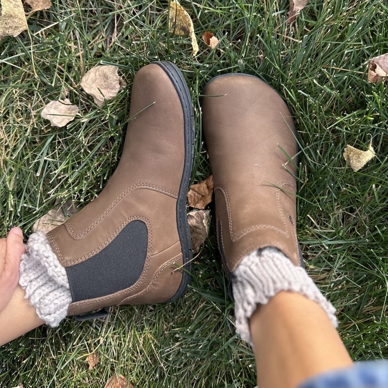 A close up of Freet Durham, a wide toe box chelsea boot in brown leather, shown from the top and side with a pair of chunky knit socks poking out the top.