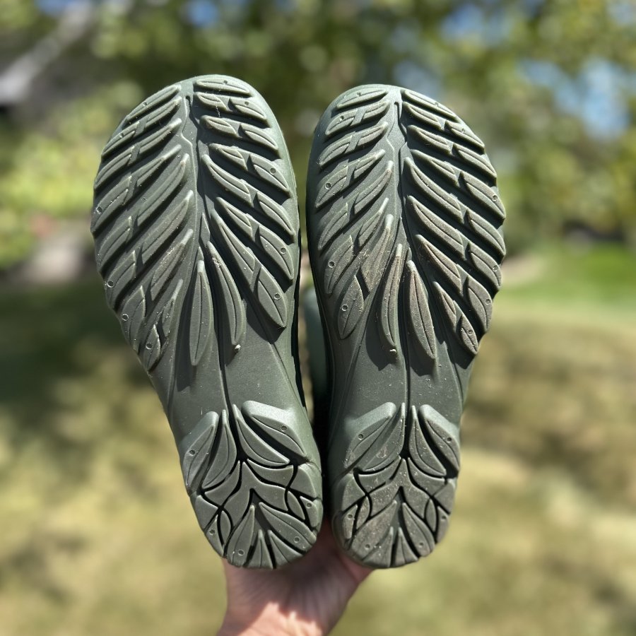A close up view of the outsole on 100% rubber rainboots, the Wildling Ranidae, a barefoot wide toe box sustainable rain boot for kids and adults. The fox logo is visible at the heel and the leaf like lugs are in a pleasing pattern at the forefoot