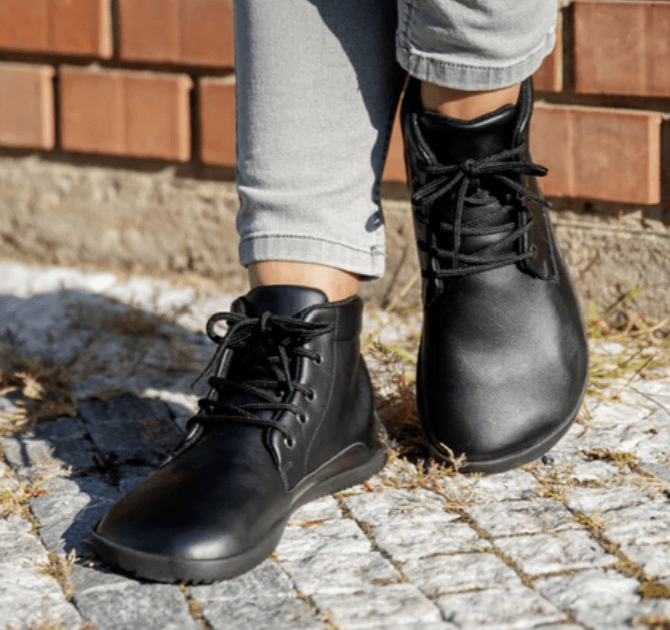 Ahinsa extra wide toe box barefoot ankle boots in black worn on a stone path