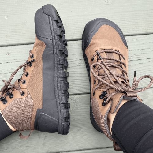 A close up of a pair of feet in Bahe Rediscover cushioned barefoot hiking boots with lugged outsole and a wide toe box. The right foot is sitting uprigth and the left foot is laying on it's side to show the side profile