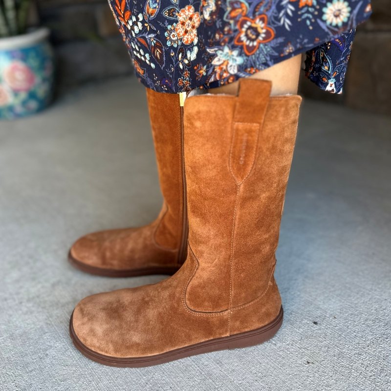 Side view of Groundies Tuscon barefoot western style boots shown from the side. The tall suede boots have pull tabs, a wide toe box, and a flat flexible outsole