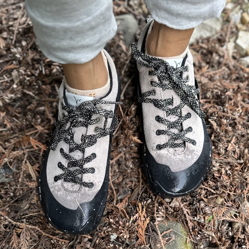 Top down view of a pair of feet in Lono WILD barefoot hiking shoes that are wet from the ground.