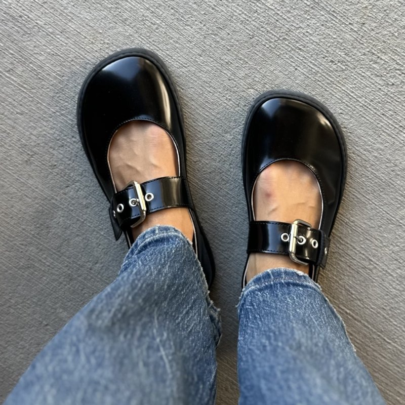 Top down view of a pair of Shapen Barefoot Coco mary janes flats in a patent black leather with a chunky buckle detail.