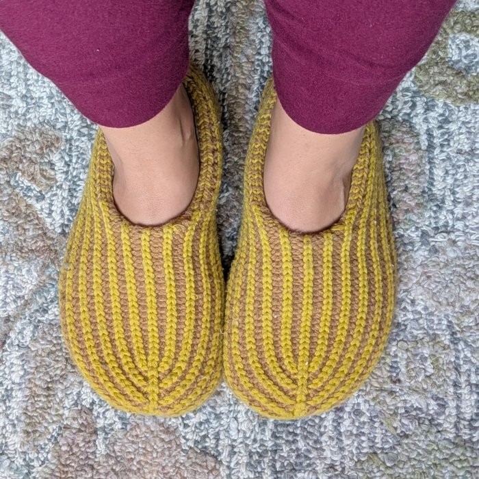 A close up of a pair of Verloop deadstock yarn slippers in a yellow and tan striped pattern